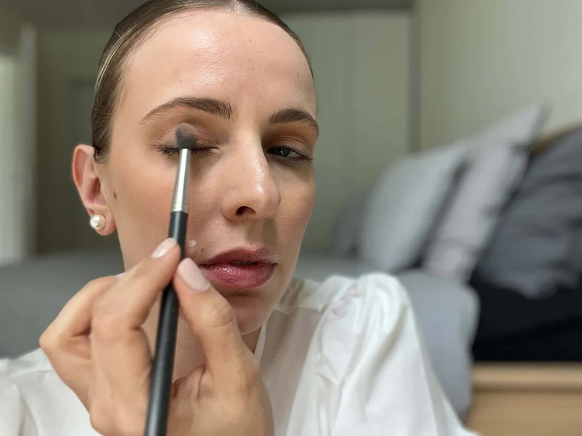 Frau verteilt nudefarbenen Lidschatten auf dem Oberlid