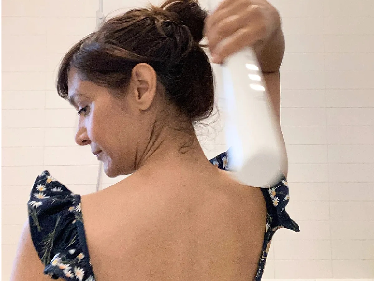 Erfahrungsberich IONIQ skincare: Frau hält den ONE Sprayer über Kopf um den Rücken einzucremen