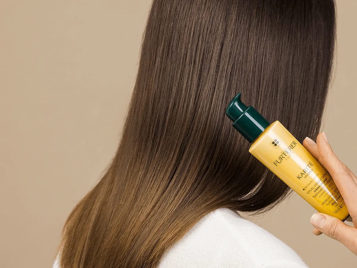 Frau mit glänzendem, gesundem Haar hält Haarpflege von René Furterer